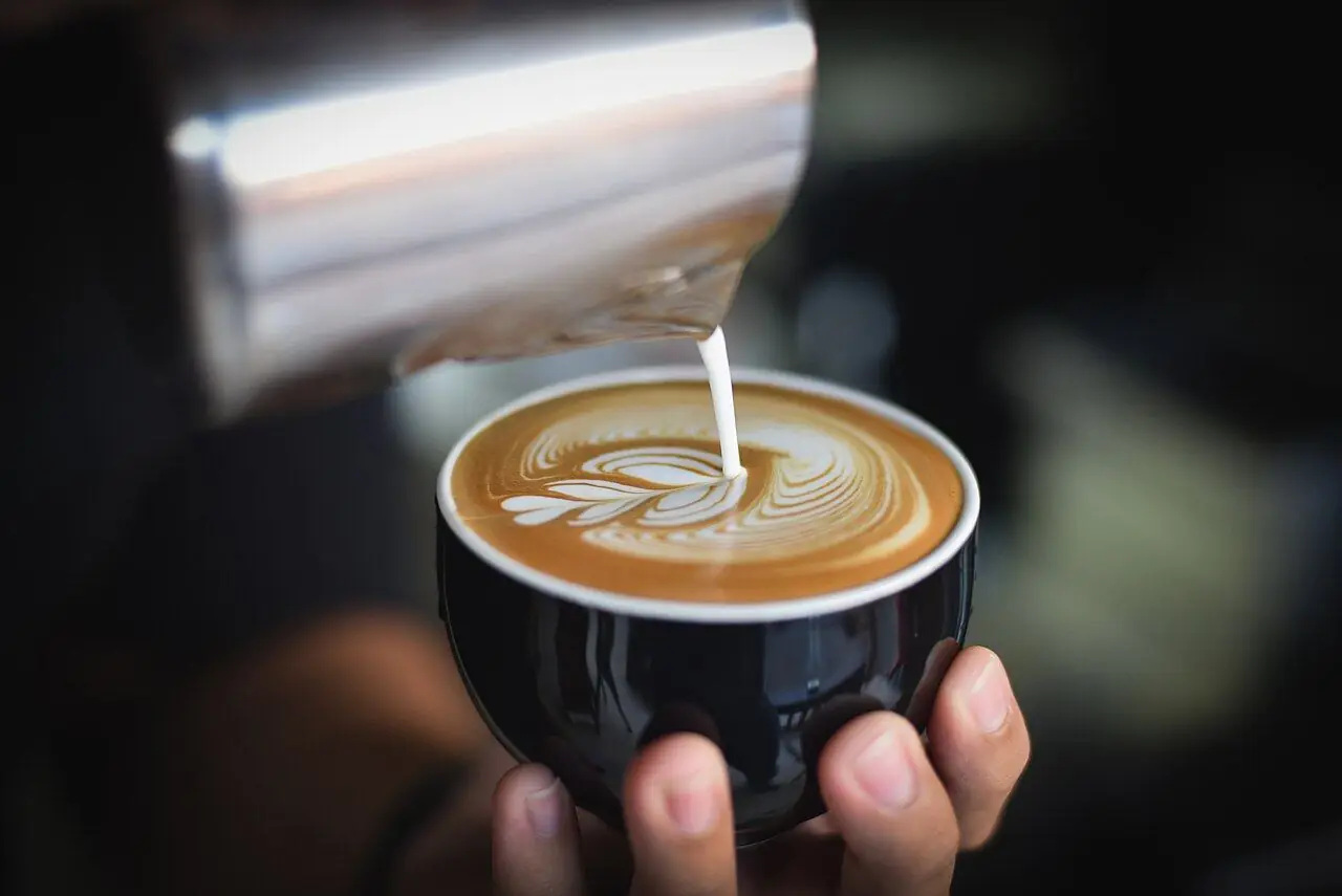 A latte being poured with heart art