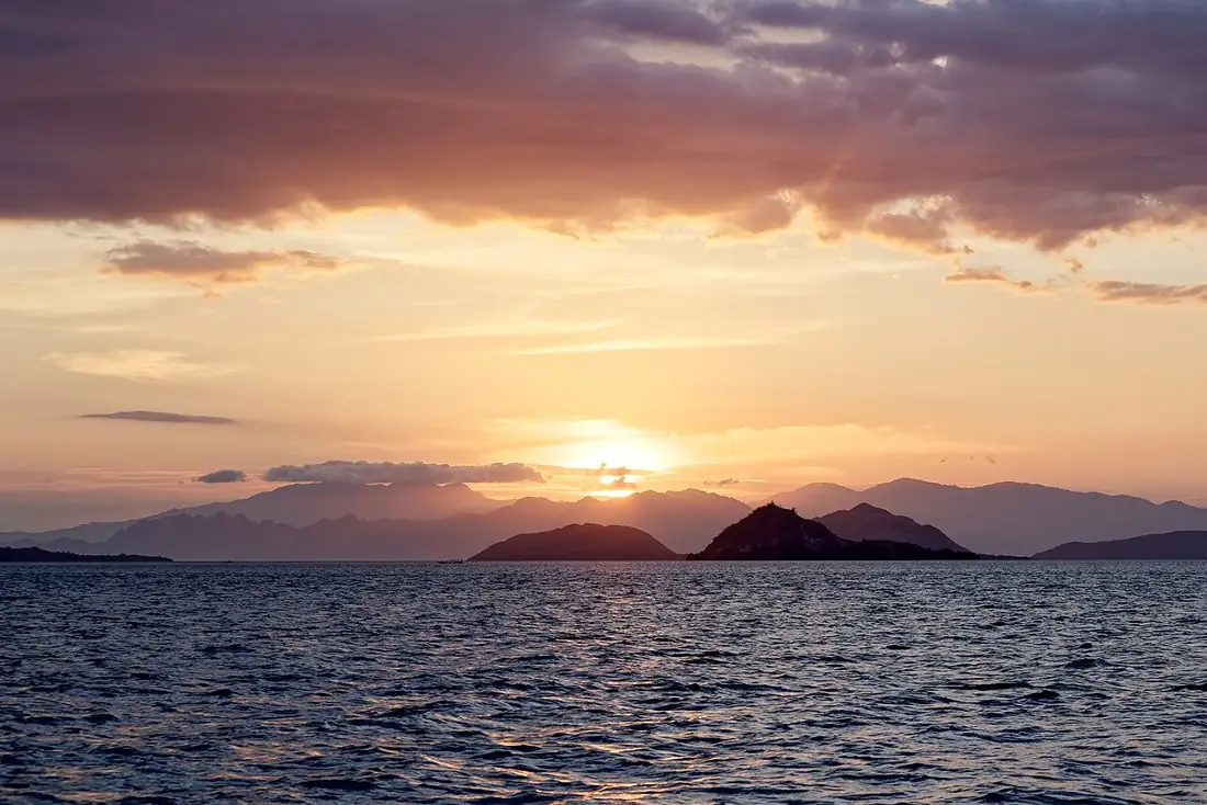 A golden sunset over the water with boats